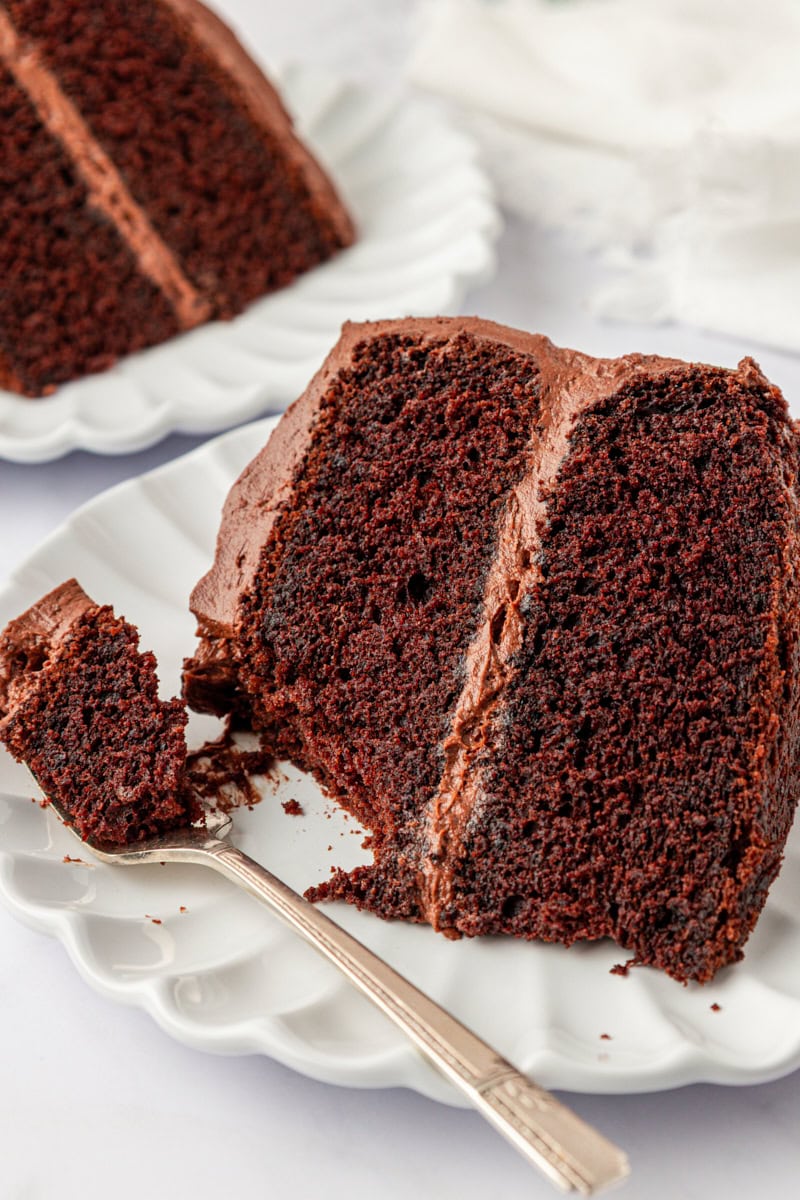 close up of a slice of devil's food cake on a plate with a bite on a fork