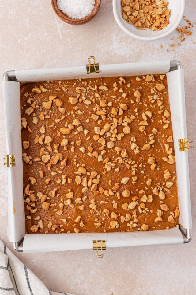peanut butter blondie batter topped with chopped peanuts before baking
