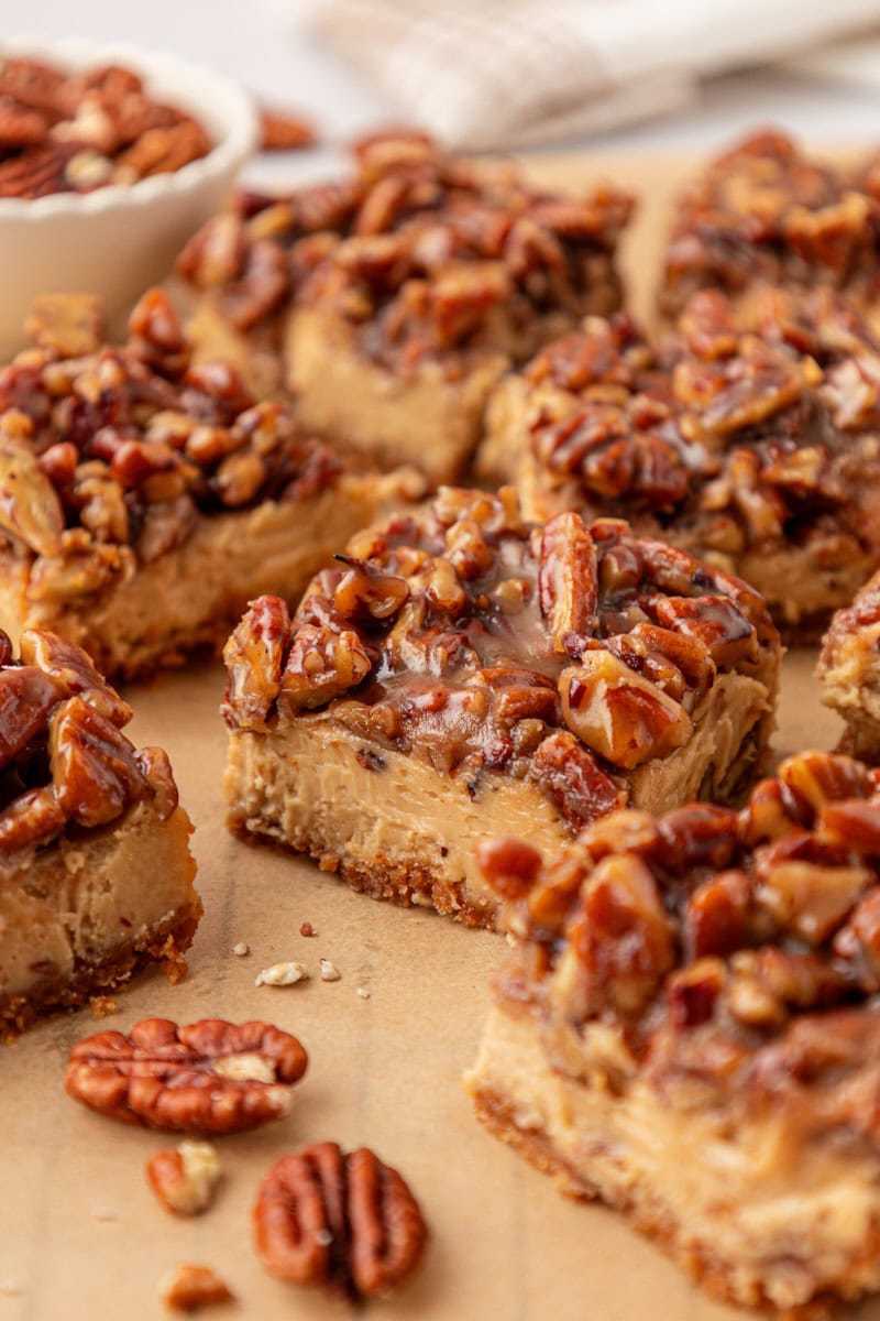 sliced pecan pie cheesecake bars showing the layers of graham cracker crust, brown sugar cheesecake, and gooey pecan topping